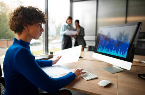 mulher-de-blusa-azul-em-escritorio-analisando-graficos-de-performance-em-um-computador