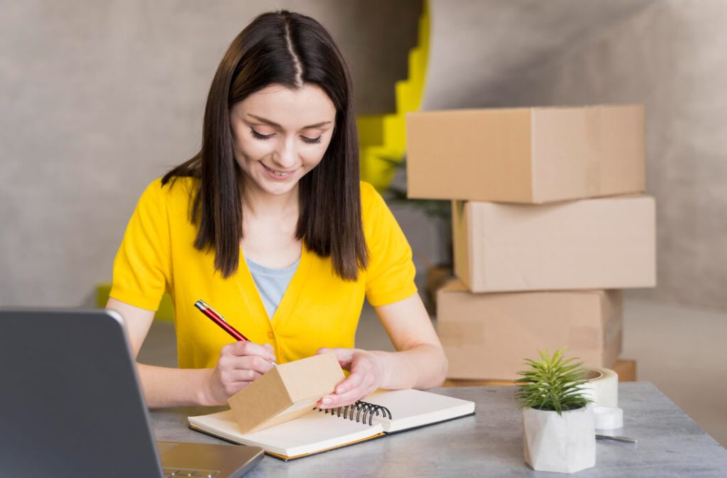 mulher-usando-blusa-amarela-preparando-caixas-para-envio-de-compra-ecommerce