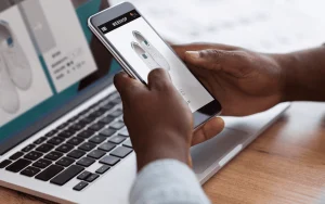 Homem-negro-fazendo-compras-on-line-com-smartphone-e-laptop-em-ambientes-fechados